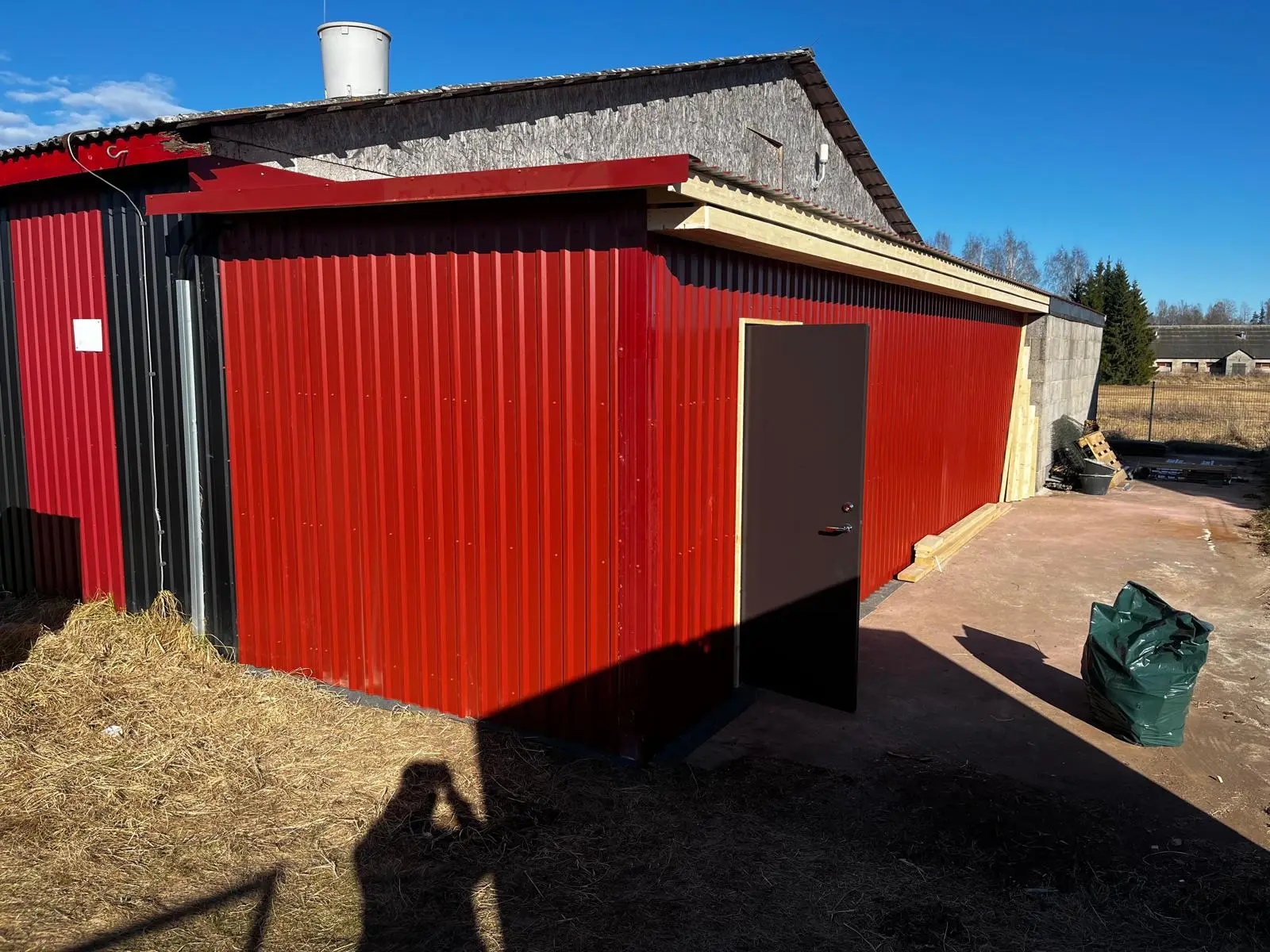 Valmis juurdeehitus punase profiilplekiga farmihoone küljes